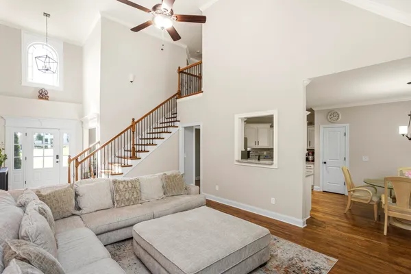 a kitchen with granite countertop a refrigerator oven a sink dishwasher and white cabinets with wooden floor