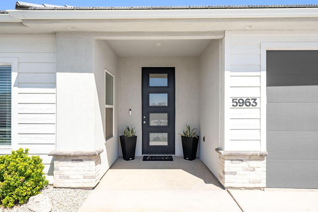 5963 Flattop Drive St. George, UT 84790 - Photo 3 of 45 Covered entry with recessed lighting, a modern paneled door featuring glass inserts, and contrasting stone-wrapped columns