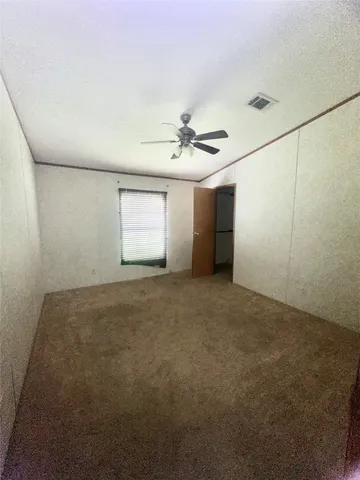 an empty room with a window and a ceiling fan