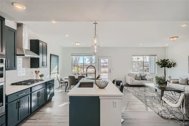 a kitchen with stainless steel appliances kitchen island granite countertop a refrigerator a sink a stove and chairs