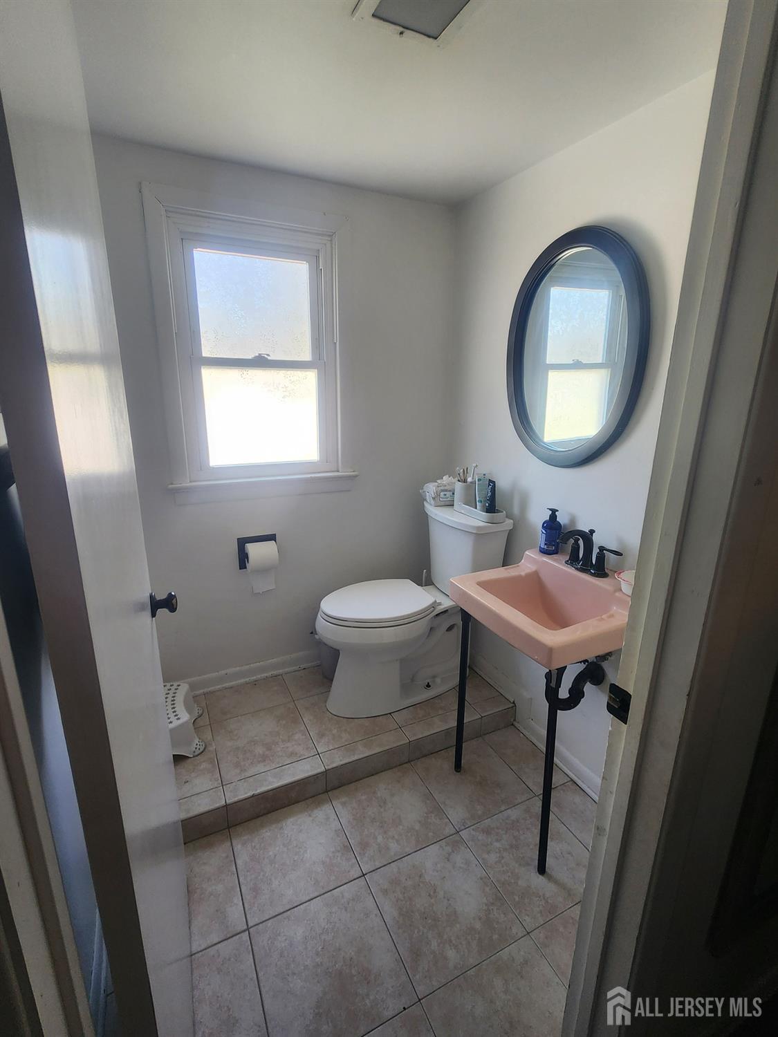 215 Summit Avenue Fords, NJ 08863 - Photo 13 of 15 a bathroom with a toilet a sink a mirror and a window