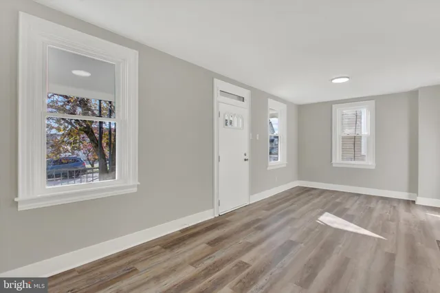 a view of an empty room with window and wooden floor