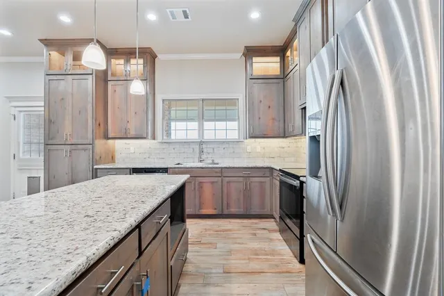 a kitchen with stainless steel appliances granite countertop a refrigerator and a sink