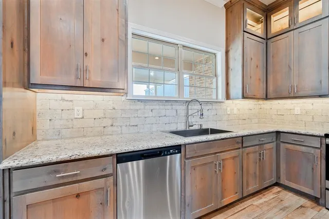 a kitchen with stainless steel appliances granite countertop a sink and a cabinets with wooden floor