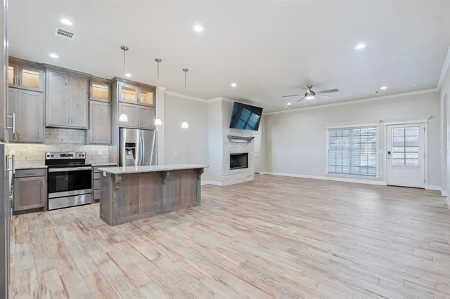 a large kitchen with stainless steel appliances a large counter top a stove and a wooden floors