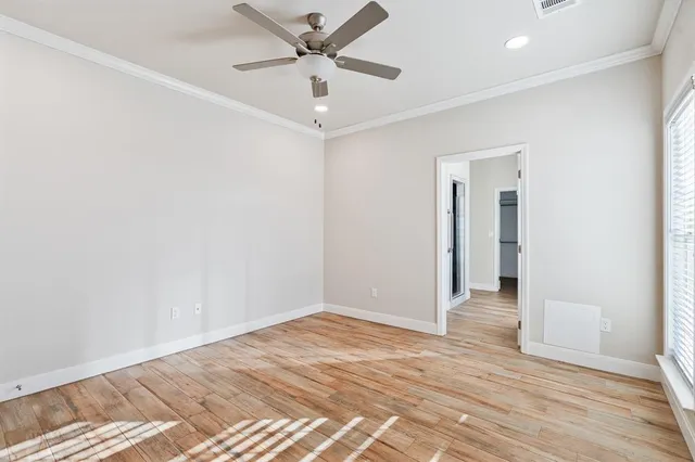 an empty room with wooden floor and a ceiling fan