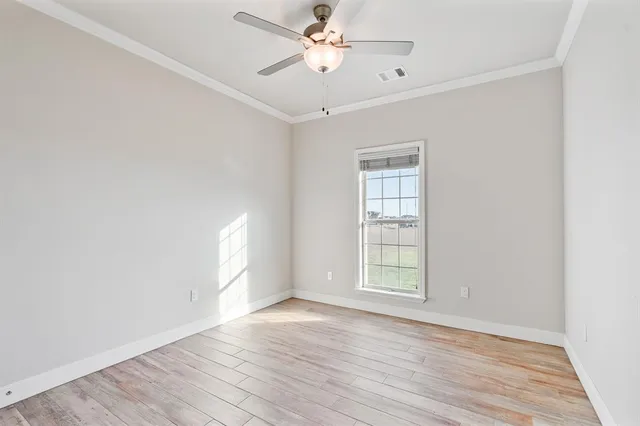 an empty room with wooden floor ceiling fan and windows