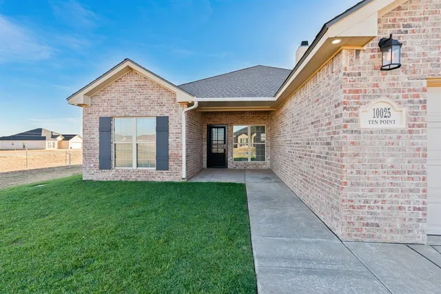 a view of a house with brick walls and a yard with plants