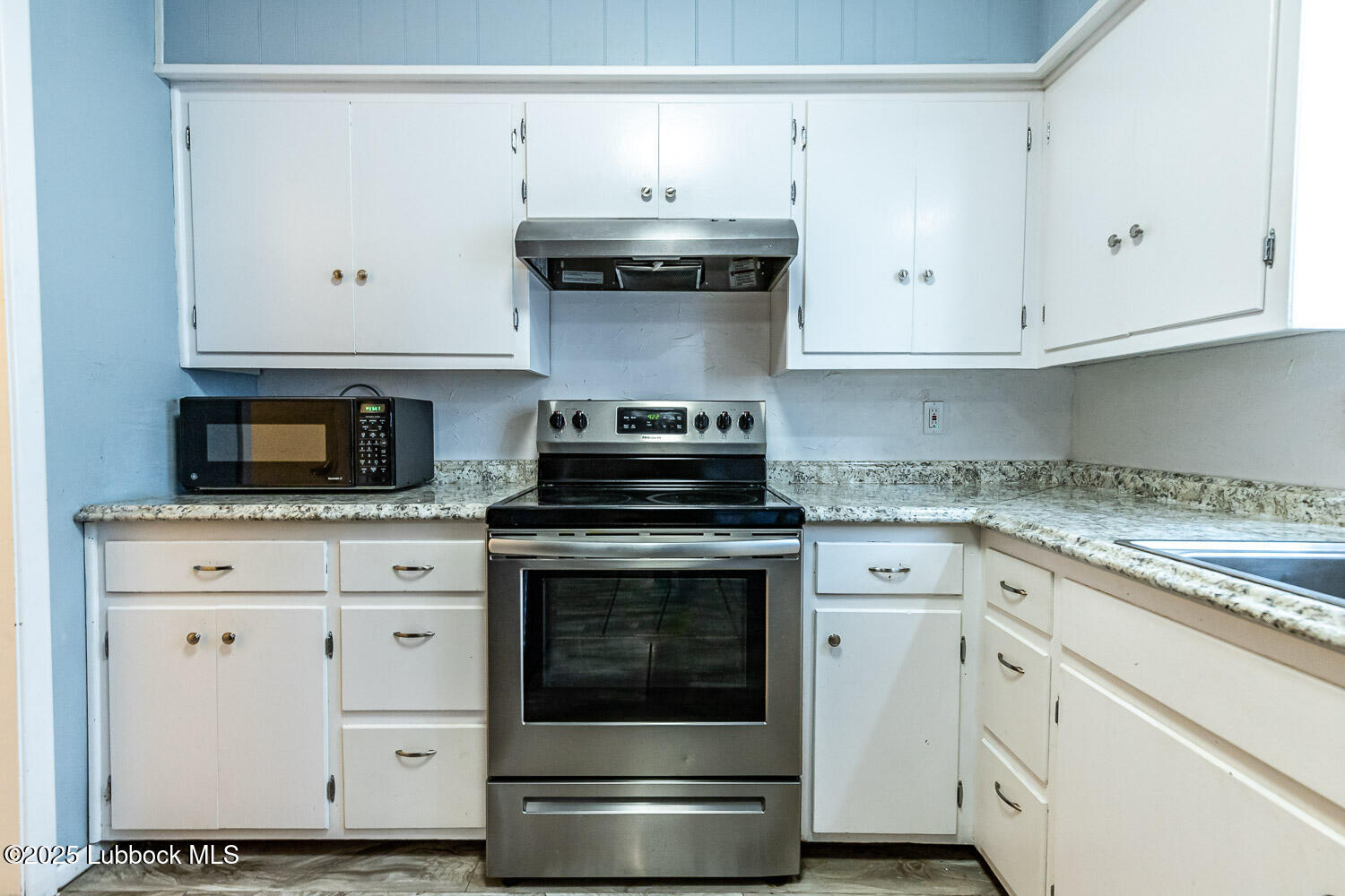 4305 52nd Street, Unit A Lubbock, TX 79413 - Photo 19 of 38 a kitchen with granite countertop white cabinets and stainless steel appliances