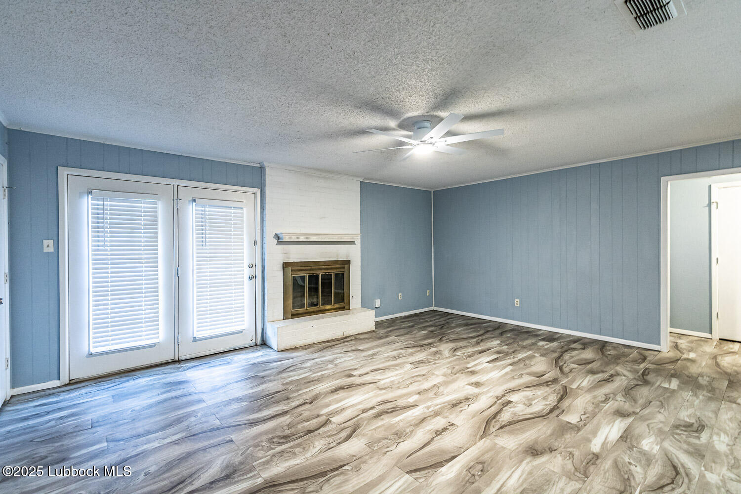 4305 52nd Street, Unit A Lubbock, TX 79413 - Photo 10 of 38 an empty room with wooden floor fireplace and ceiling fan