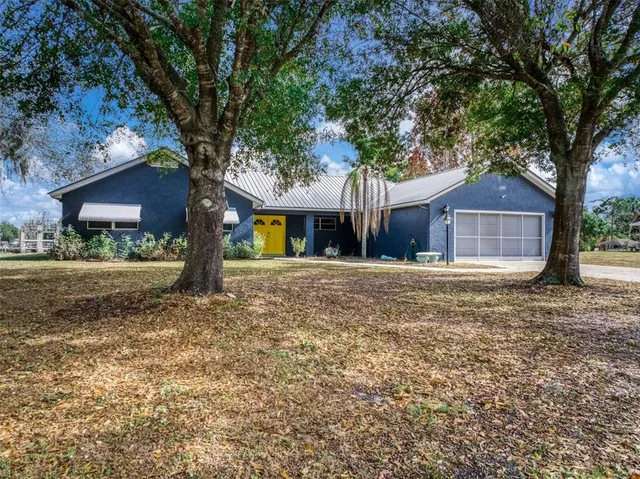 a front view of a house with a yard and large tree