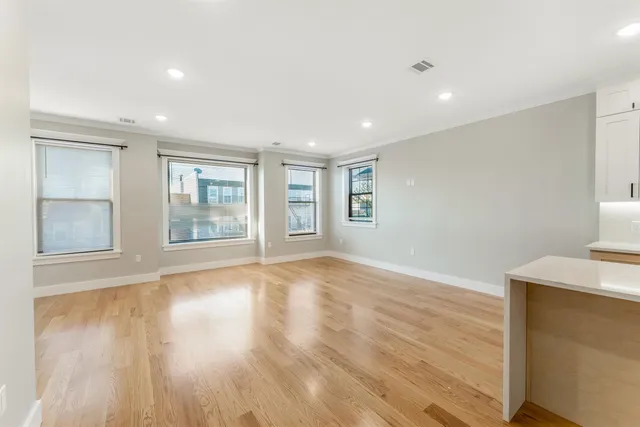 a view of an empty room with a window and wooden floor