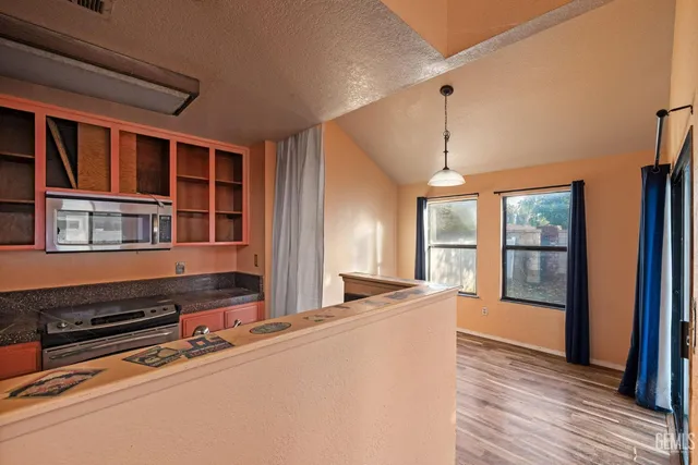 a living room with stainless steel appliances wooden floors and large window