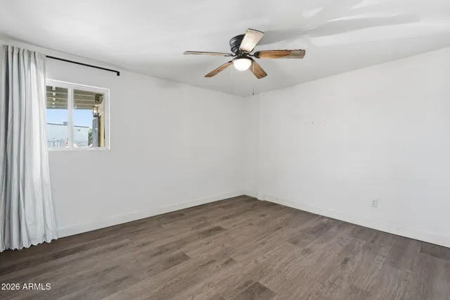 an empty room with wooden floor fan and windows