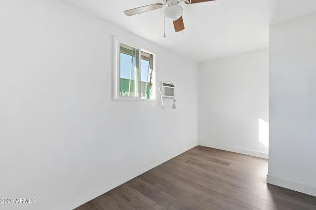 an empty room with wooden floor chandelier fan and windows