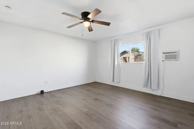 an empty room with wooden floor and ceiling fan