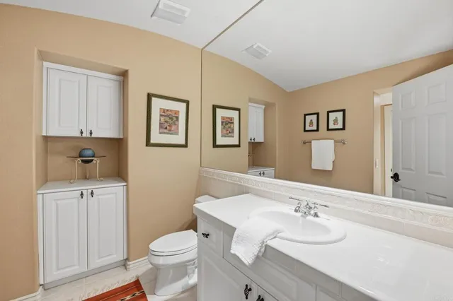 a bathroom with a granite countertop toilet sink and mirror