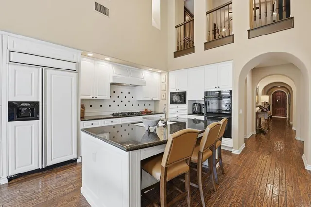 a kitchen with stainless steel appliances granite countertop a table chairs refrigerator and sink