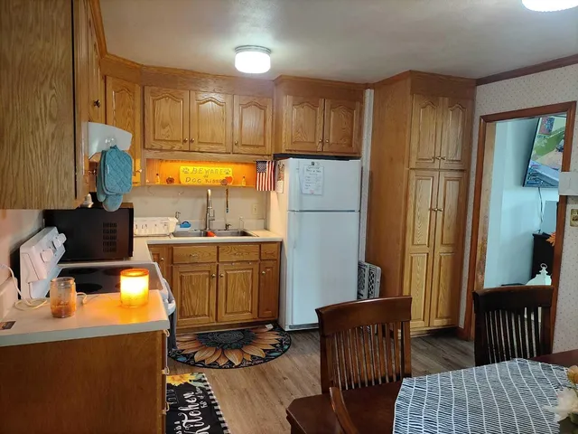 a kitchen with stainless steel appliances granite countertop a refrigerator a sink dishwasher a stove a dining table and chairs with wooden floor
