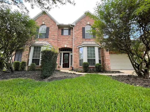 a front view of a house with a yard and trees