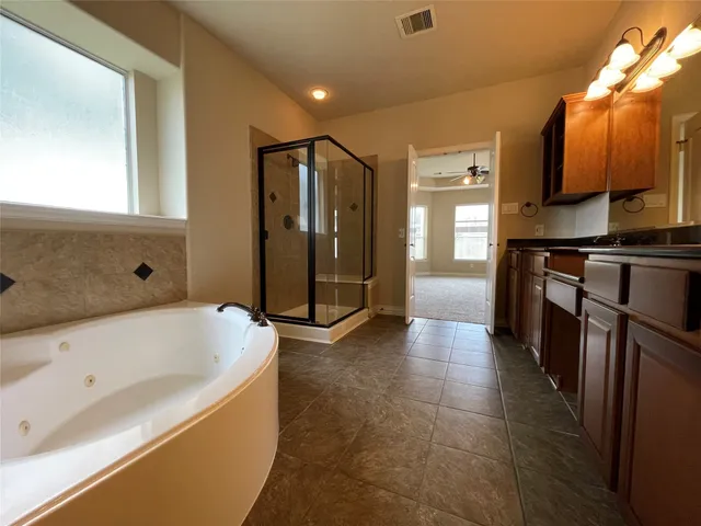 a bathroom with a tub a mirror and shower