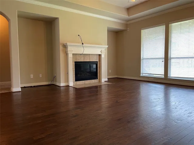 an empty room with wooden floor fireplace and windows