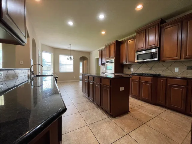 a large kitchen with stainless steel appliances wooden cabinets a stove and a sink