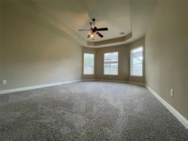 an empty room with windows and ceiling fan
