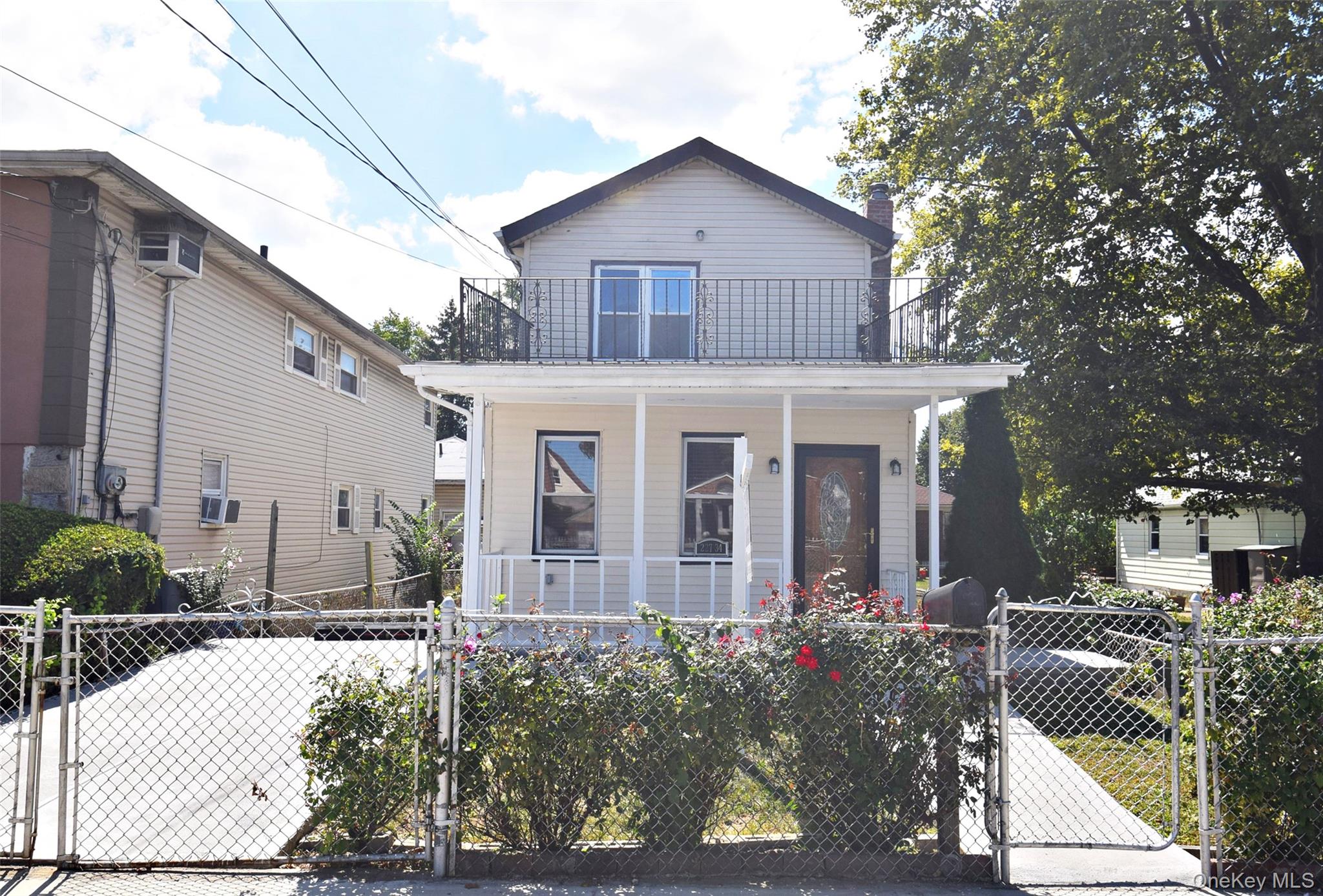 227-34 112th Road Queens, NY 11429 - Photo 1 of 1 View of front of house featuring a gate, a fenced front yard, a porch, and a chimney