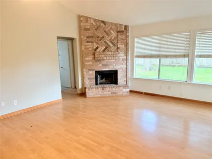 an empty room with windows and fireplace