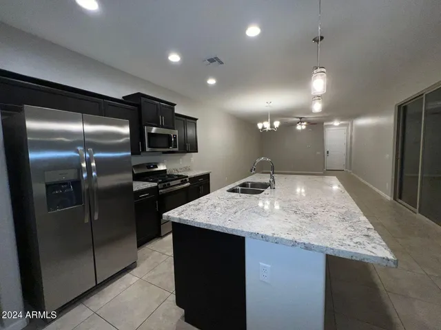 a kitchen with stainless steel appliances granite countertop a sink a refrigerator and a counter top