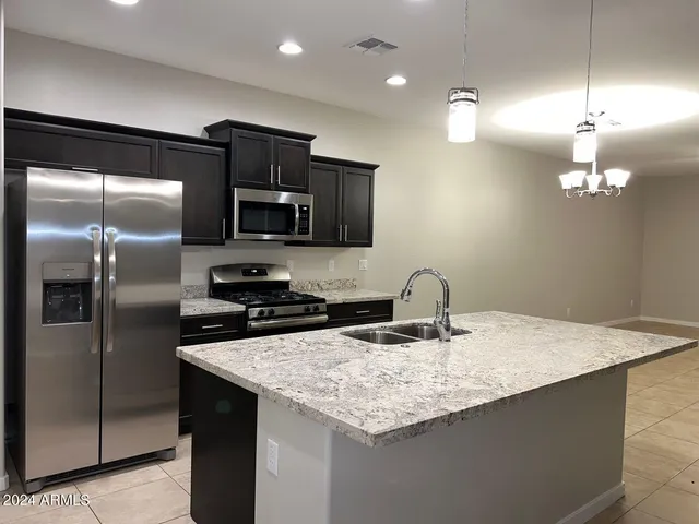 a kitchen with stainless steel appliances granite countertop a sink a microwave a refrigerator and a stove