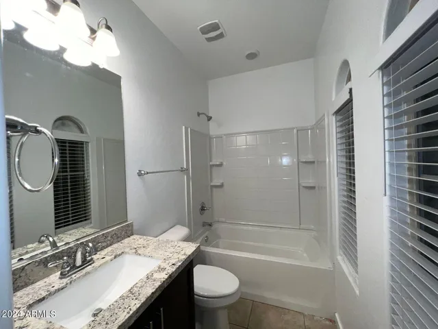 a bathroom with a granite countertop sink toilet mirror and shower