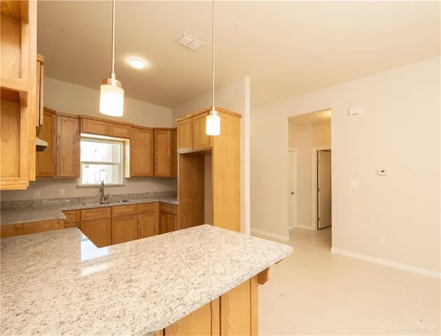 a kitchen with stainless steel appliances kitchen island granite countertop a sink refrigerator and cabinets