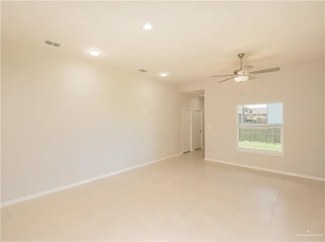 an empty room with a fan & a window