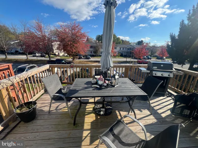 a view of a roof deck with table and chairs a barbeque with wooden floor and fence
