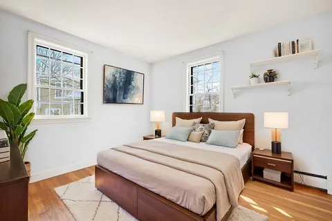 a bedroom with bed and a potted plant on the dresser