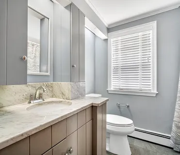 a bathroom with a granite countertop sink and a toilet