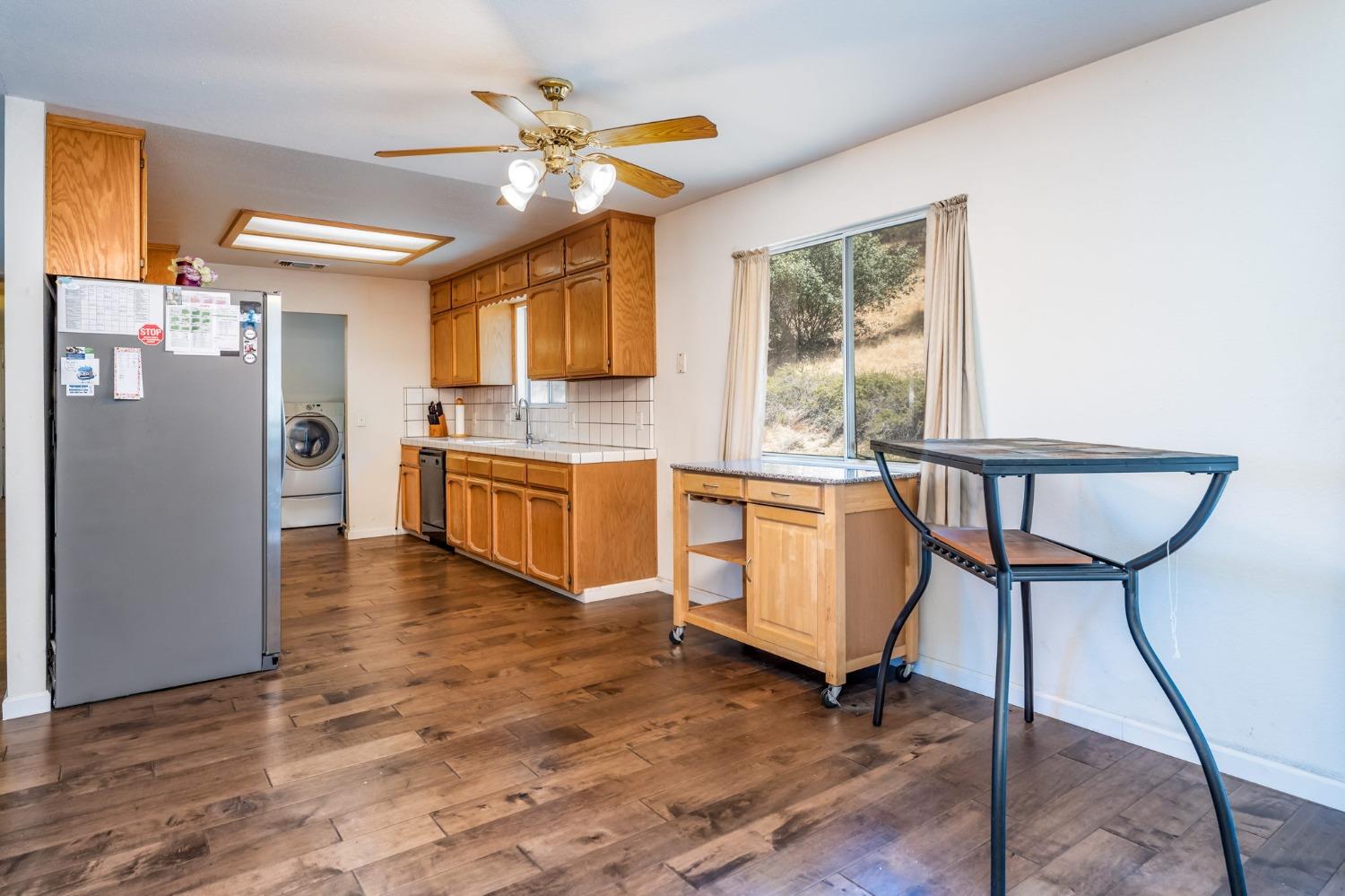 43142 Ellen Mine Road Coarsegold, CA 93614 - Photo 13 of 29 a kitchen with stainless steel appliances granite countertop a stove top oven a sink dishwasher a dining table and chairs with wooden floor