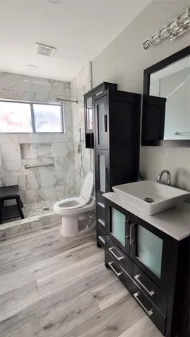 a bathroom with a sink a toilet a mirror and shower