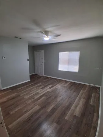 a view of an empty room with wooden floor and a window