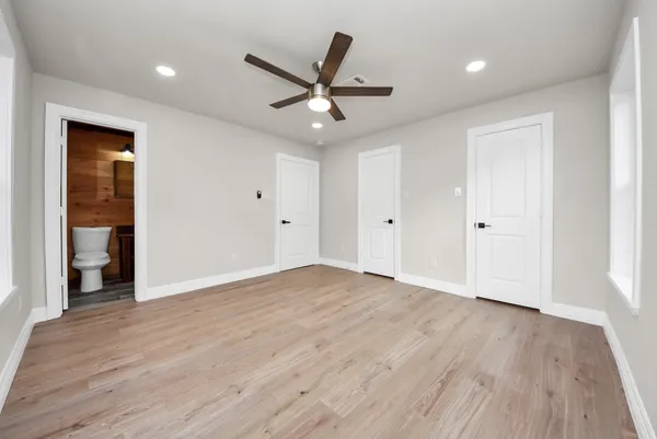 a view of an empty room with wooden floor and a ceiling fan