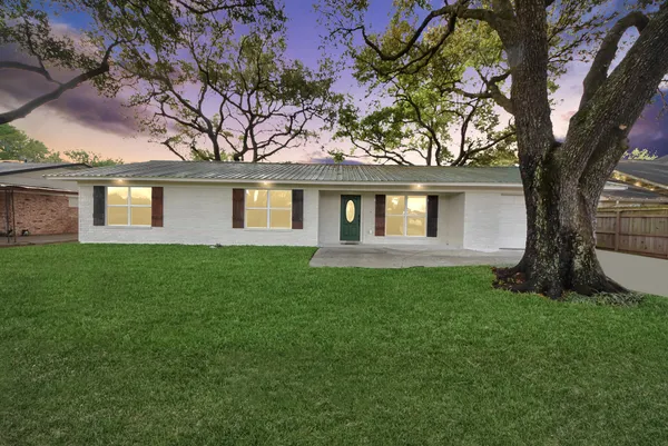 a view of a yard in front of a house with large trees