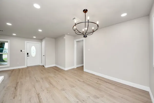 a view of empty room with wooden floor and chandelier