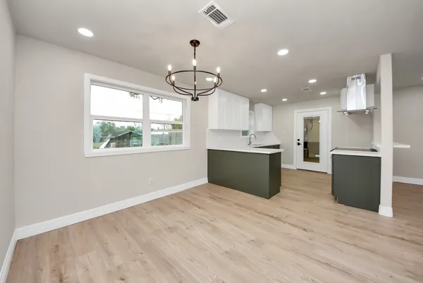 a view of kitchen with kitchen island stainless steel appliances wooden floor cabinets and a window