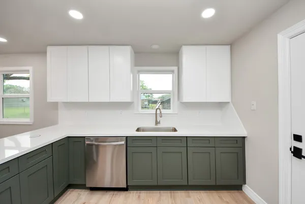 a kitchen with white cabinets a sink and dishwasher