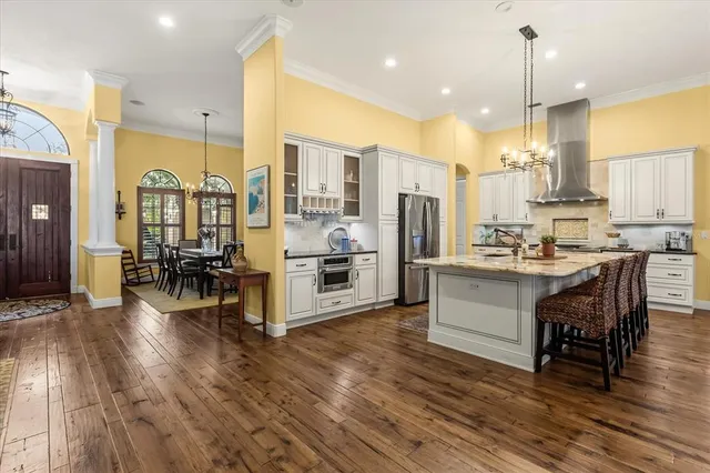 a kitchen with stainless steel appliances a dining table chairs stove and white cabinets