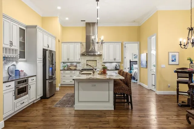 a kitchen with stainless steel appliances granite countertop a refrigerator a stove and a wooden floors