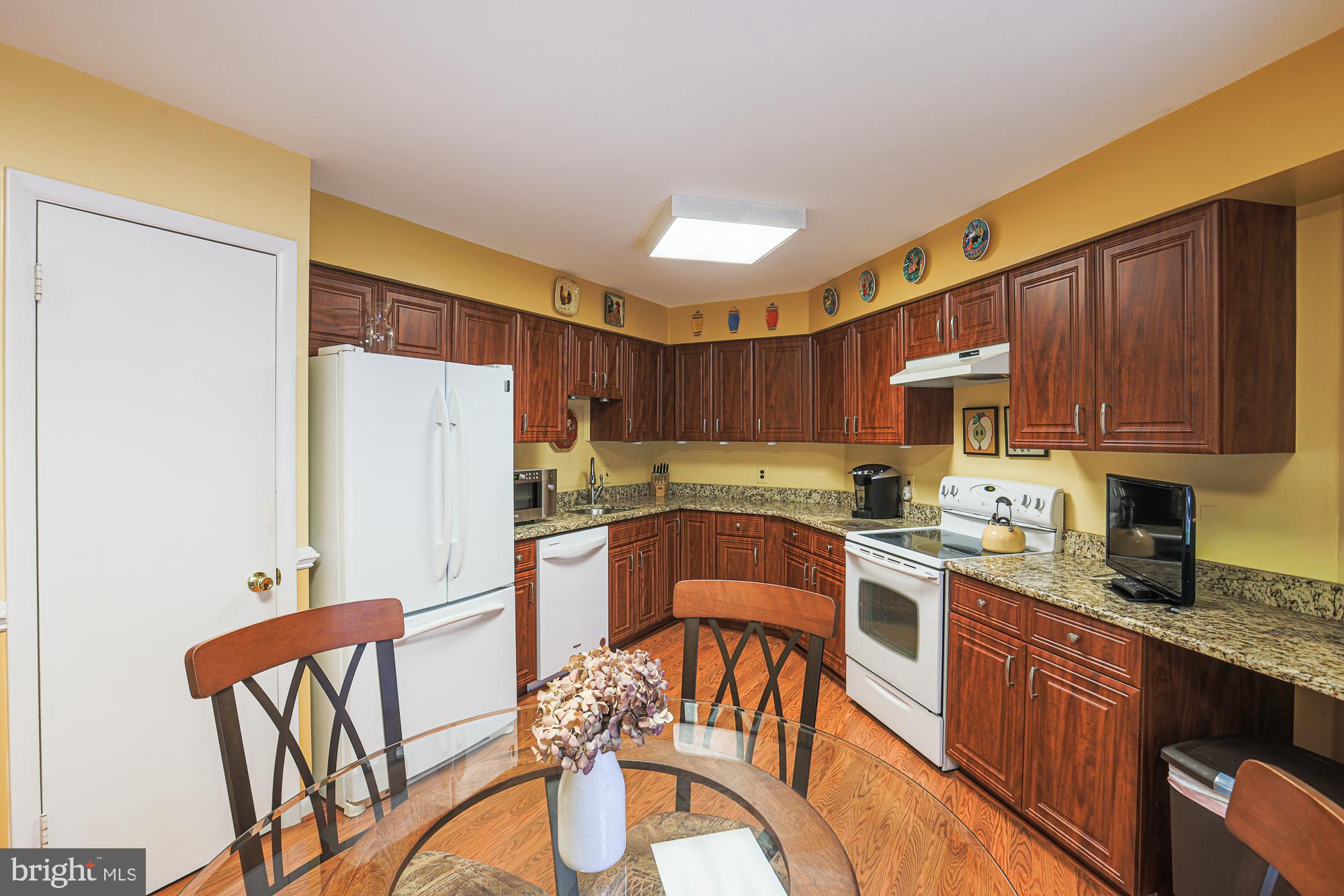 3041 Fallstaff Road, Unit 304D Baltimore, MD 21209 - Photo 26 of 39 a kitchen with stainless steel appliances granite countertop a refrigerator a stove a sink dishwasher a dining table and chairs with wooden floor