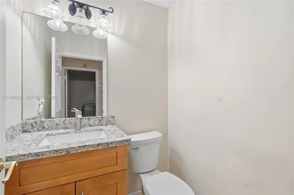 a bathroom with a granite countertop sink vanity mirror and toilet